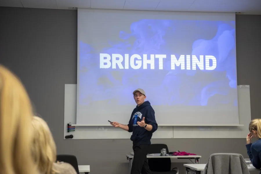 Visa större: Sibbe Silvén håller en AI-workshop i ett konferensrum med deltagare vid bord